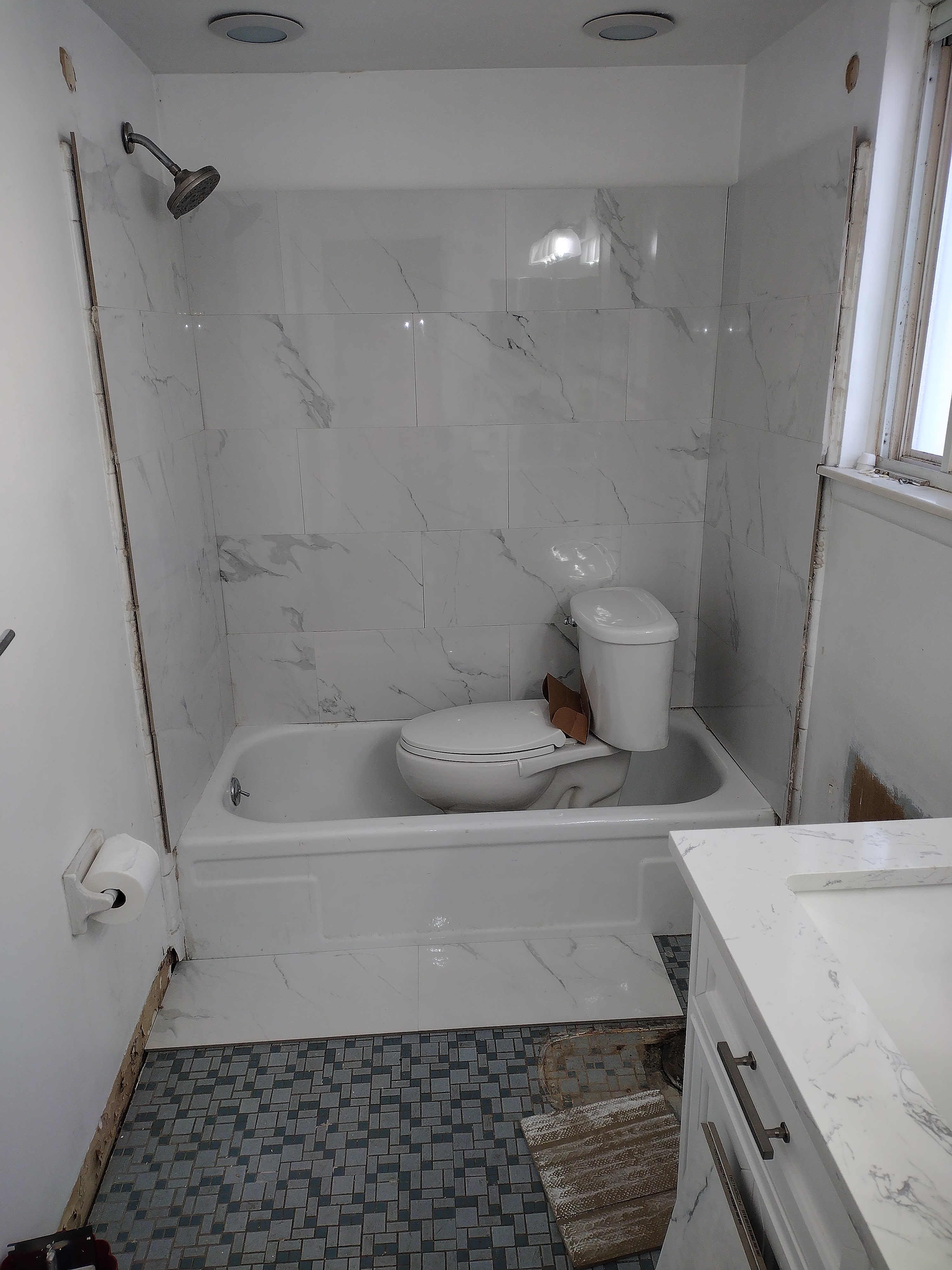 Bathroom renovation in progress — marble tile and tub installation